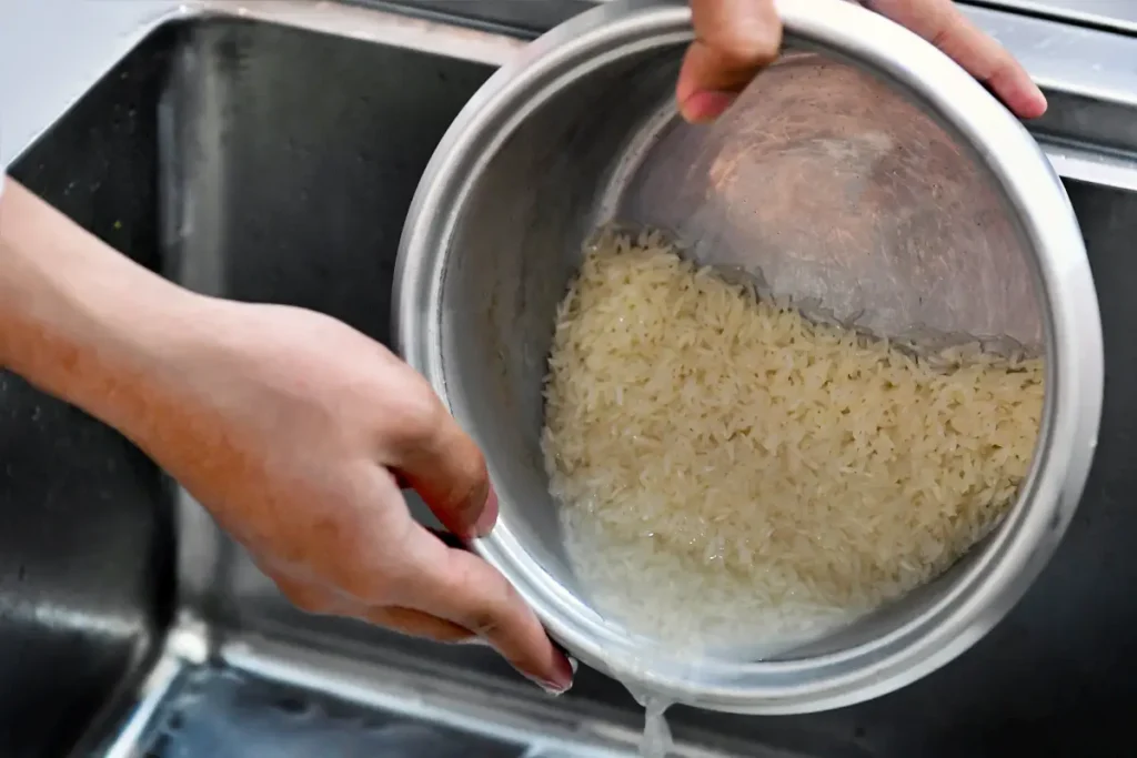 Mencuci beras dan menuangkan air cucian beras