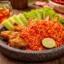 Ayam geprek dan sambal yang sangat pedas serta lalapan dalam wadah cobek batu.