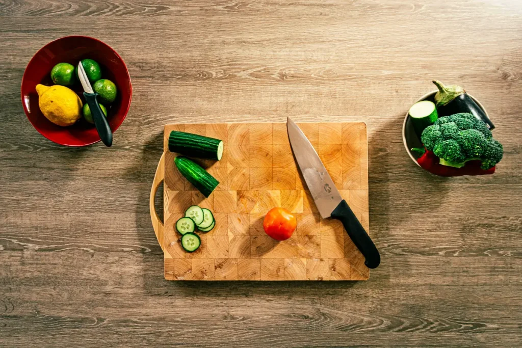 Talenan dengan pisau dan potongan sayuran di atasnya.