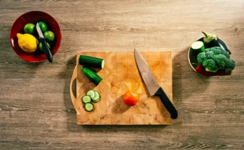 Talenan dengan pisau dan potongan sayuran di atasnya.