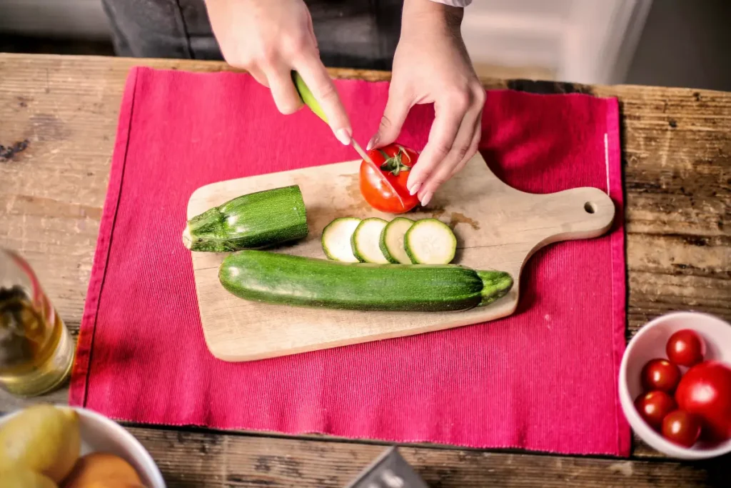 Memotong sayuran dengan pisau dengan alas talenan.
