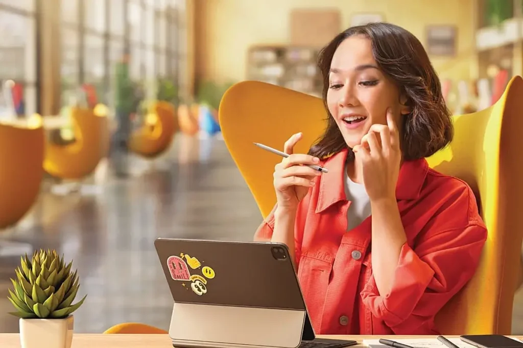 Seorang perempuan pekerja sedang bekerja di kafe dan memperhatikan layar tablet