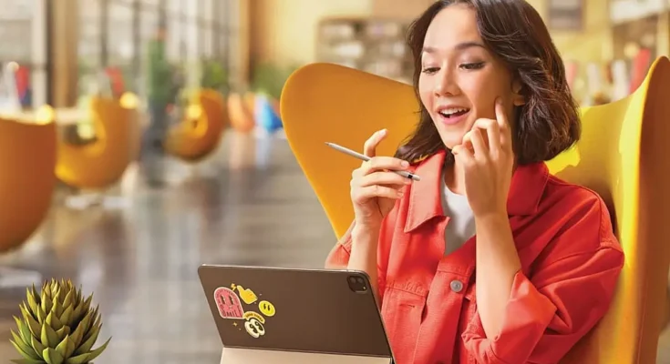 Seorang perempuan pekerja sedang bekerja di kafe dan memperhatikan layar tablet