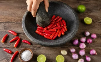 Mengulek cabai dengan ulekan dan cobek tradisional dari batu